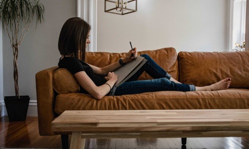 The essence of exceptional living a person laying on a couch writing